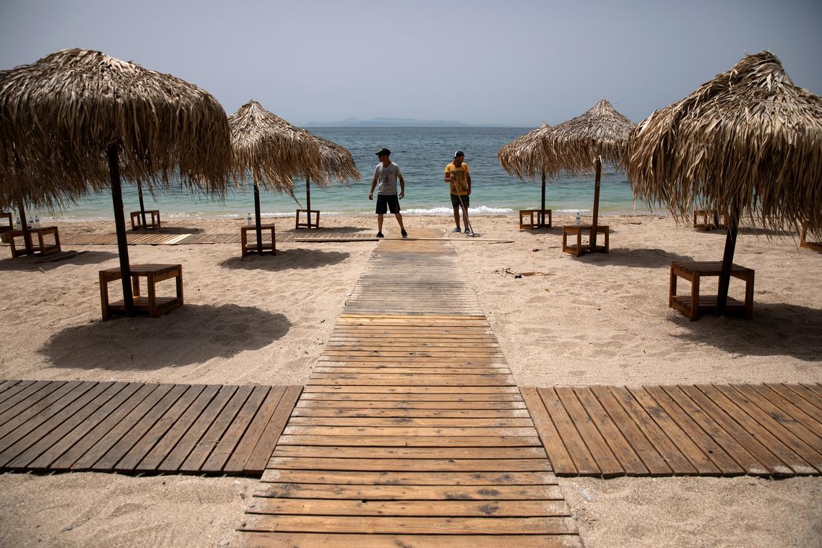 Greeks return to beaches in heatwave, but keep umbrellas apart