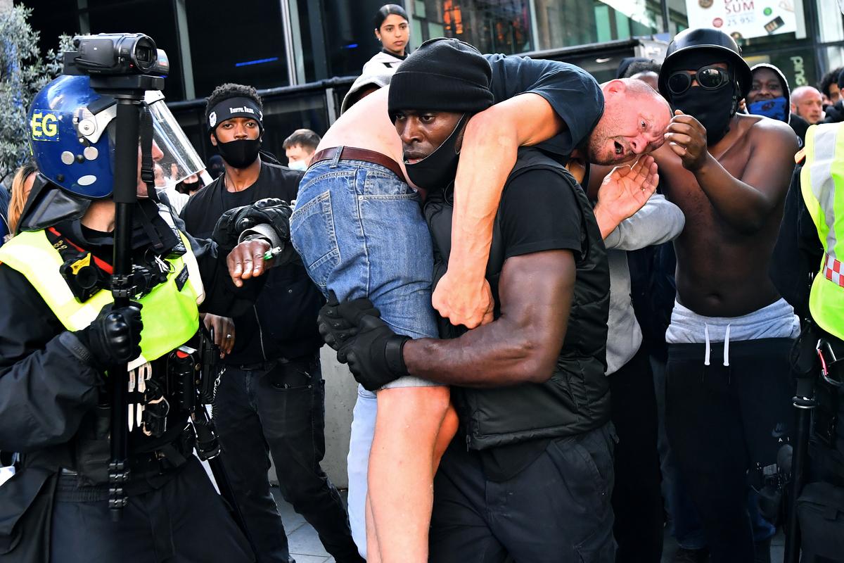 A picture and its story: Black man carries suspected far-right protester to safety