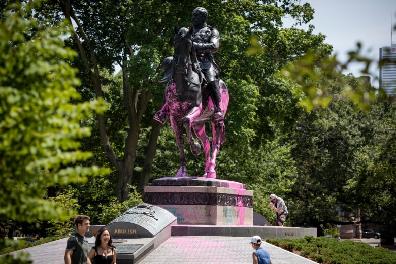 Police charge 3 people after protesters splatter paint on statues in Toronto | CBC News